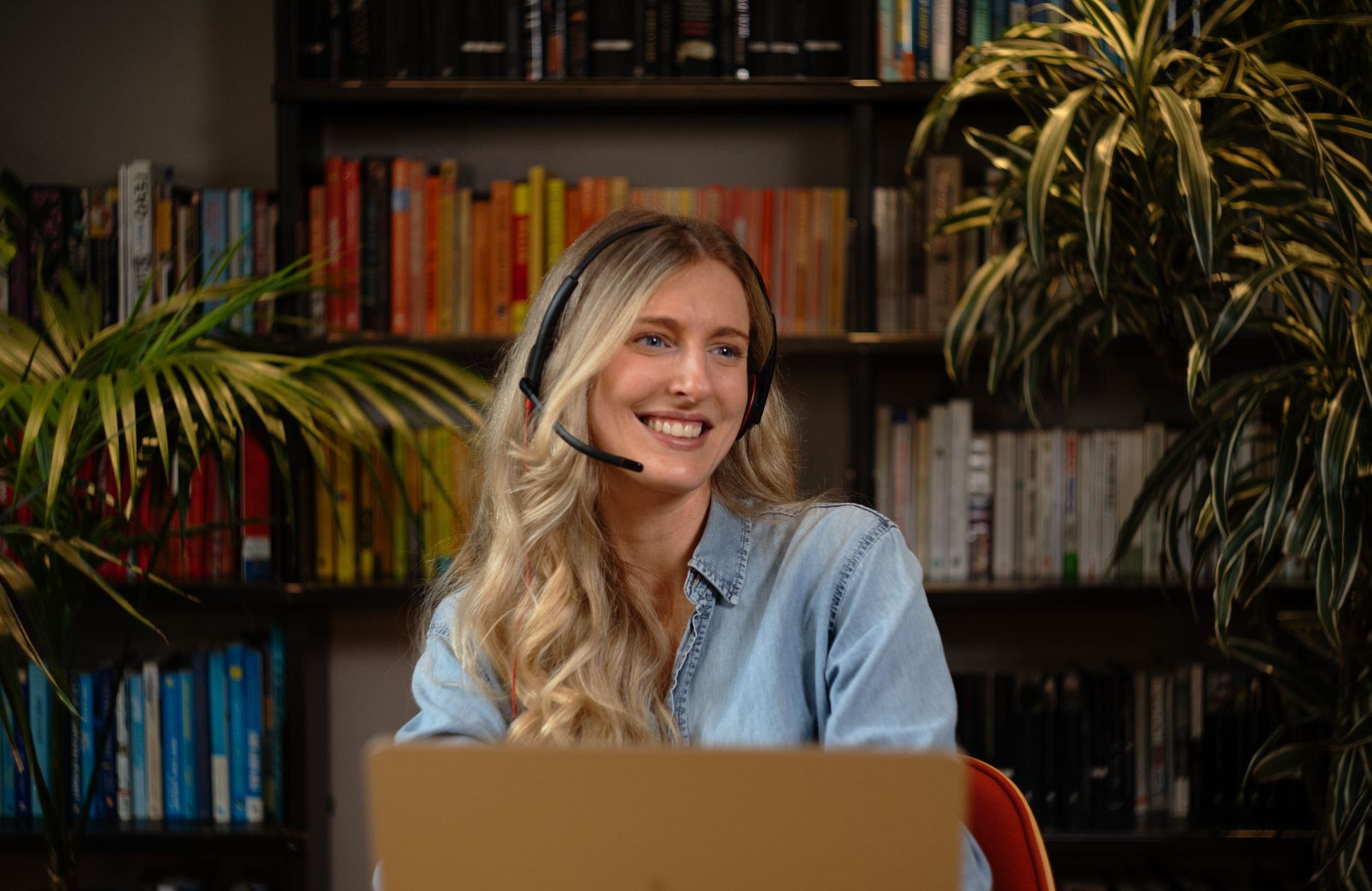 a woman with a headset on, laptop in front of her