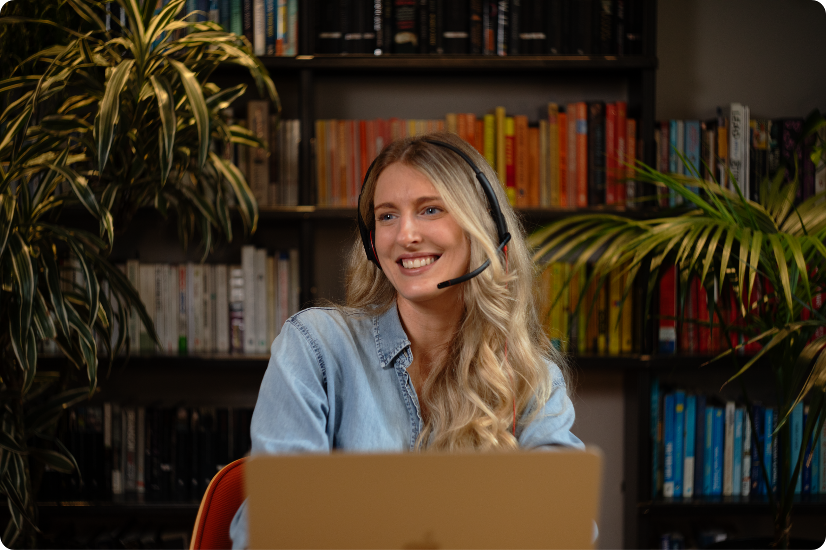 a woman with a headset on, sitting at desk with laptop