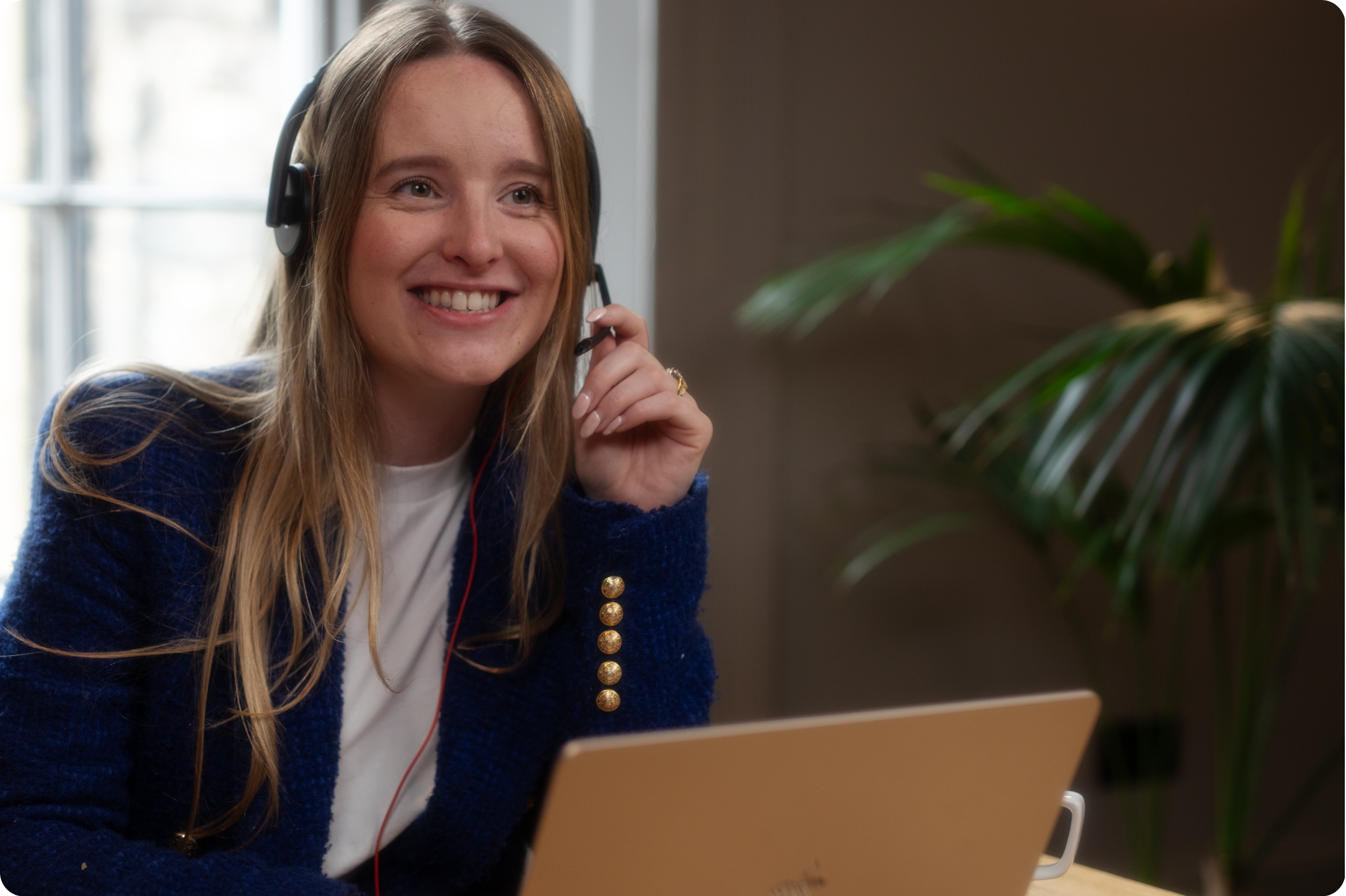 a woman with a headset on, sitting at desk with laptop
