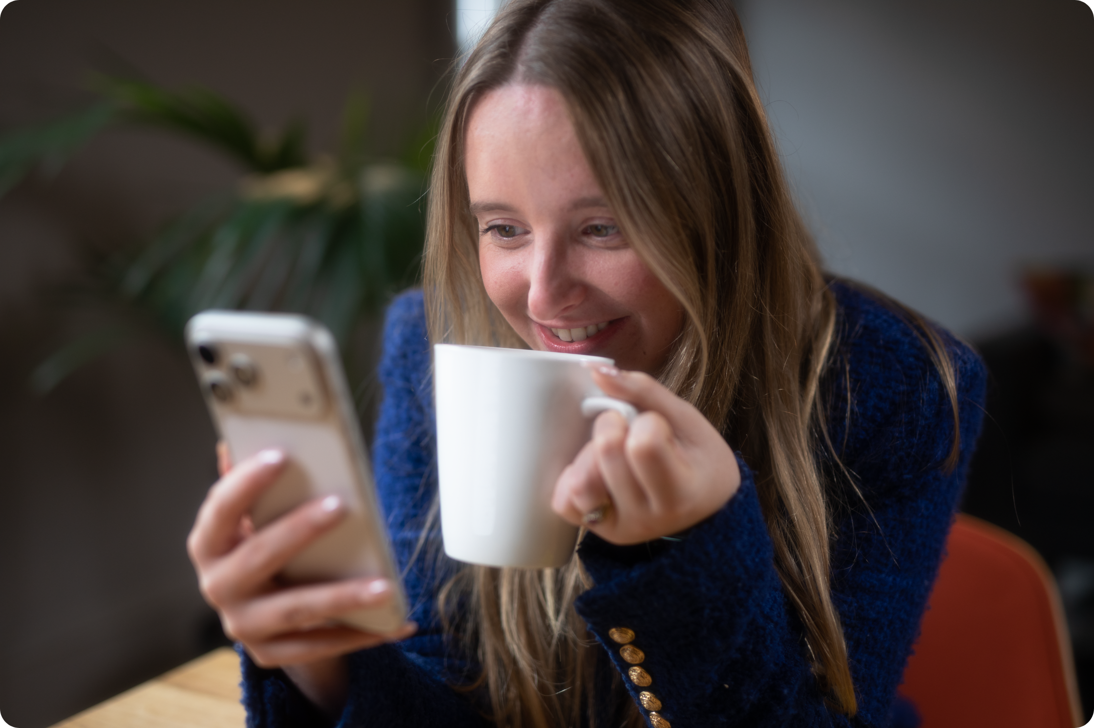 woman holding mug, looking at phone
