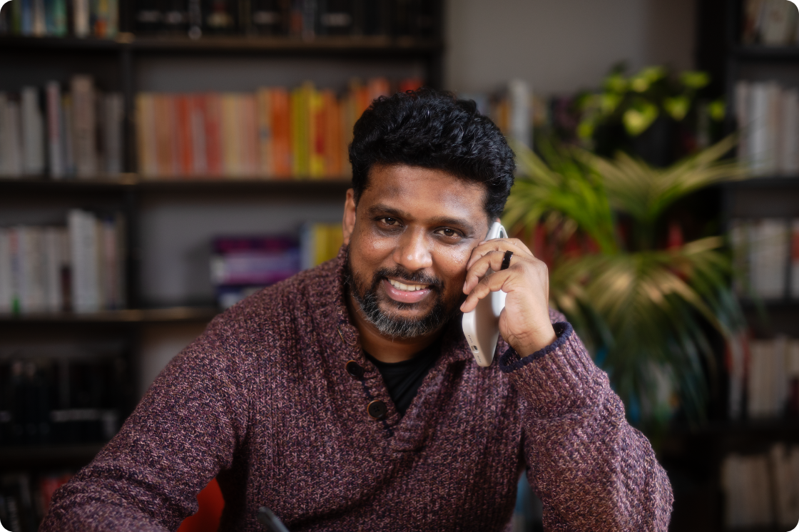a man holding a phone on a call, sitting at desk  