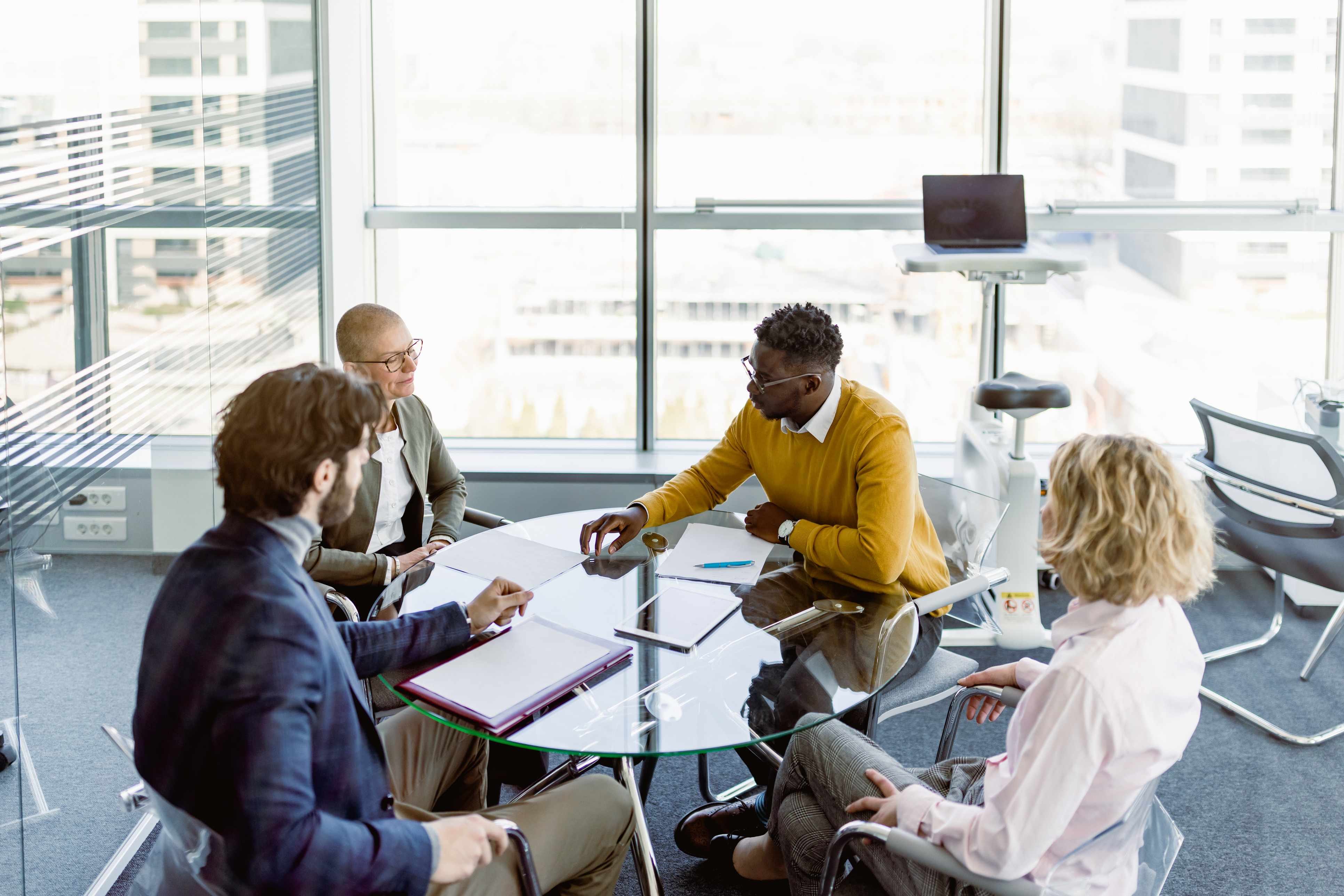 four people sitting around a class table, talking